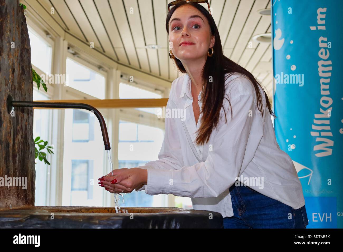 Kururlaub in Bad Lausick: Junge Frau am Heilwasserbrunnen, Erfrischung mit Quellwasser im sächsischen Heilbad, Wellness & Gesundheit, Sachsen Stock Photo