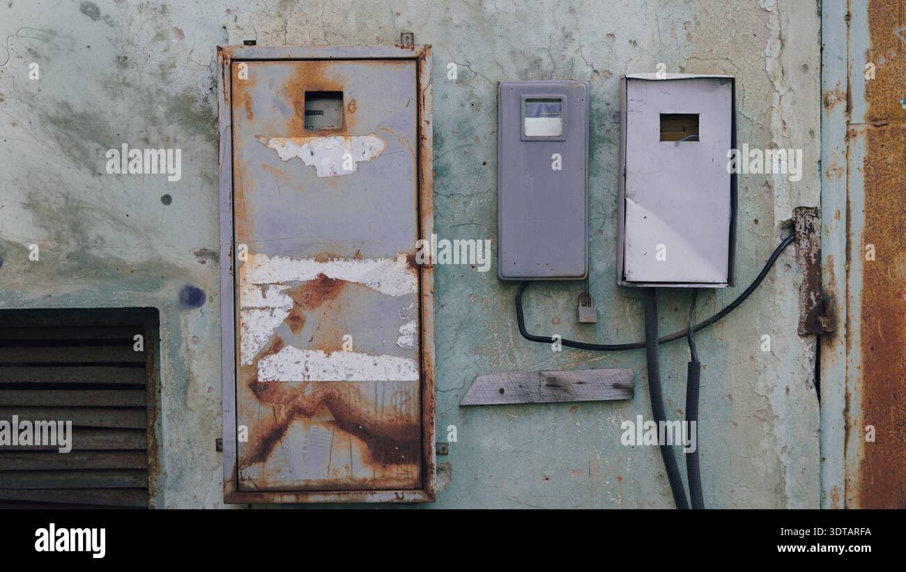 Two old electrical panels with rust and peeling paint attached to a ...