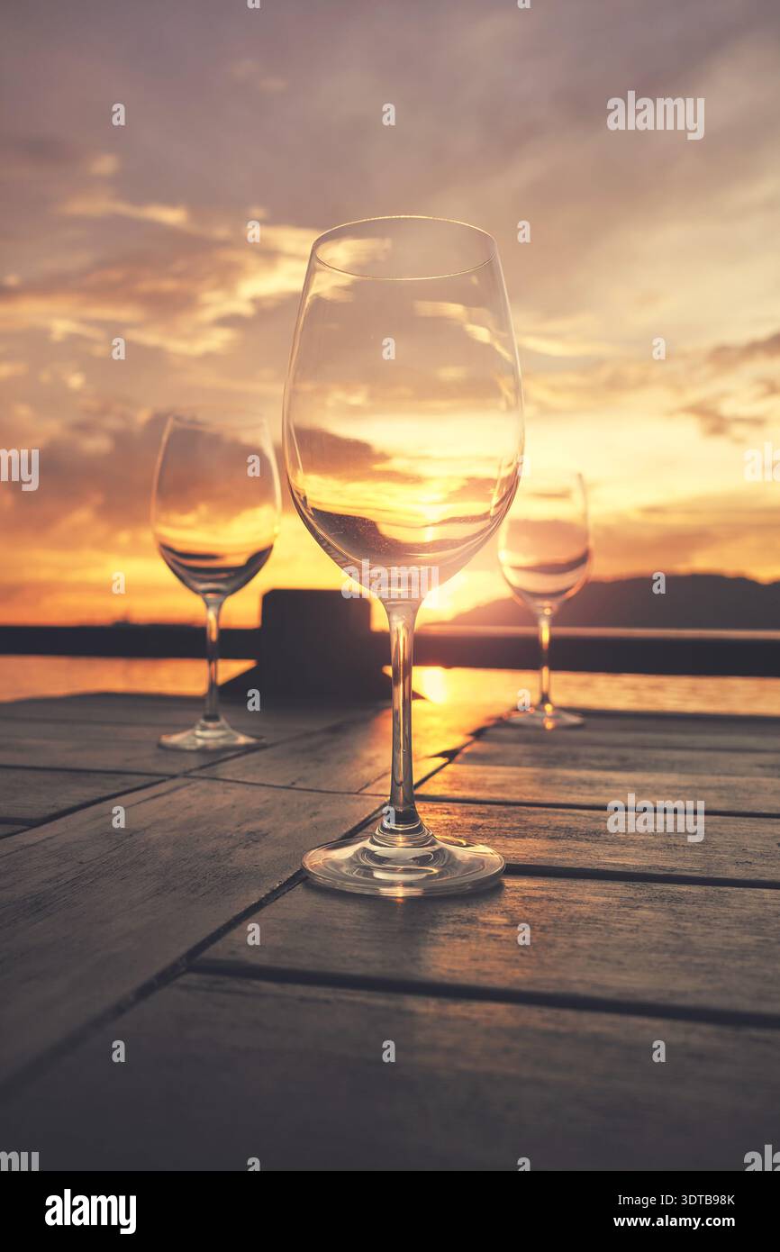 Empty wine glasses placed on a table at sunset, selective focus. Stock Photo
