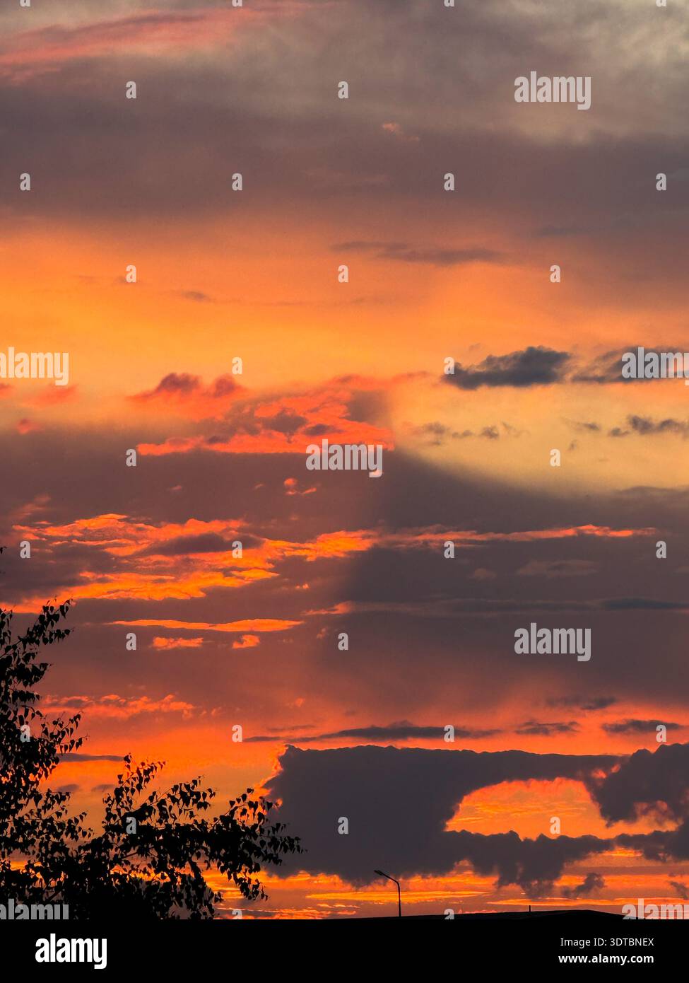 Fiery orange sunset sky with dark clouds Stock Photo