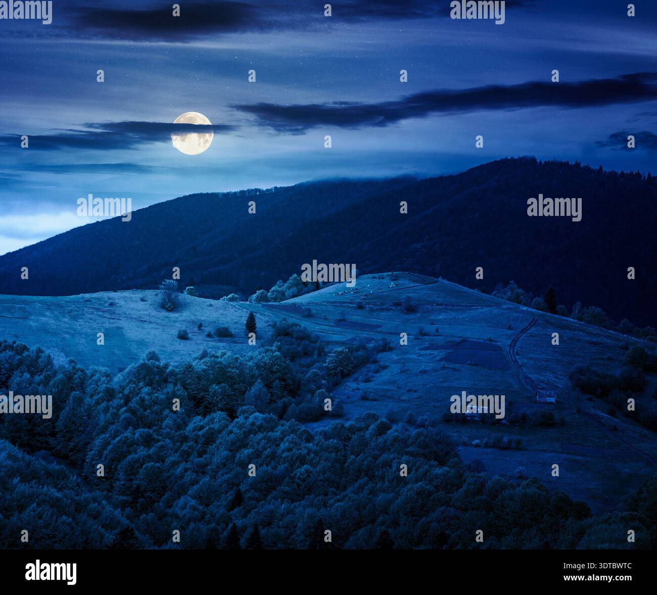 rural mountain landscape during spring at night. wonderful countryside scenery on a cold weather in full moon light. cloudy sky above rolling hills in Stock Photo