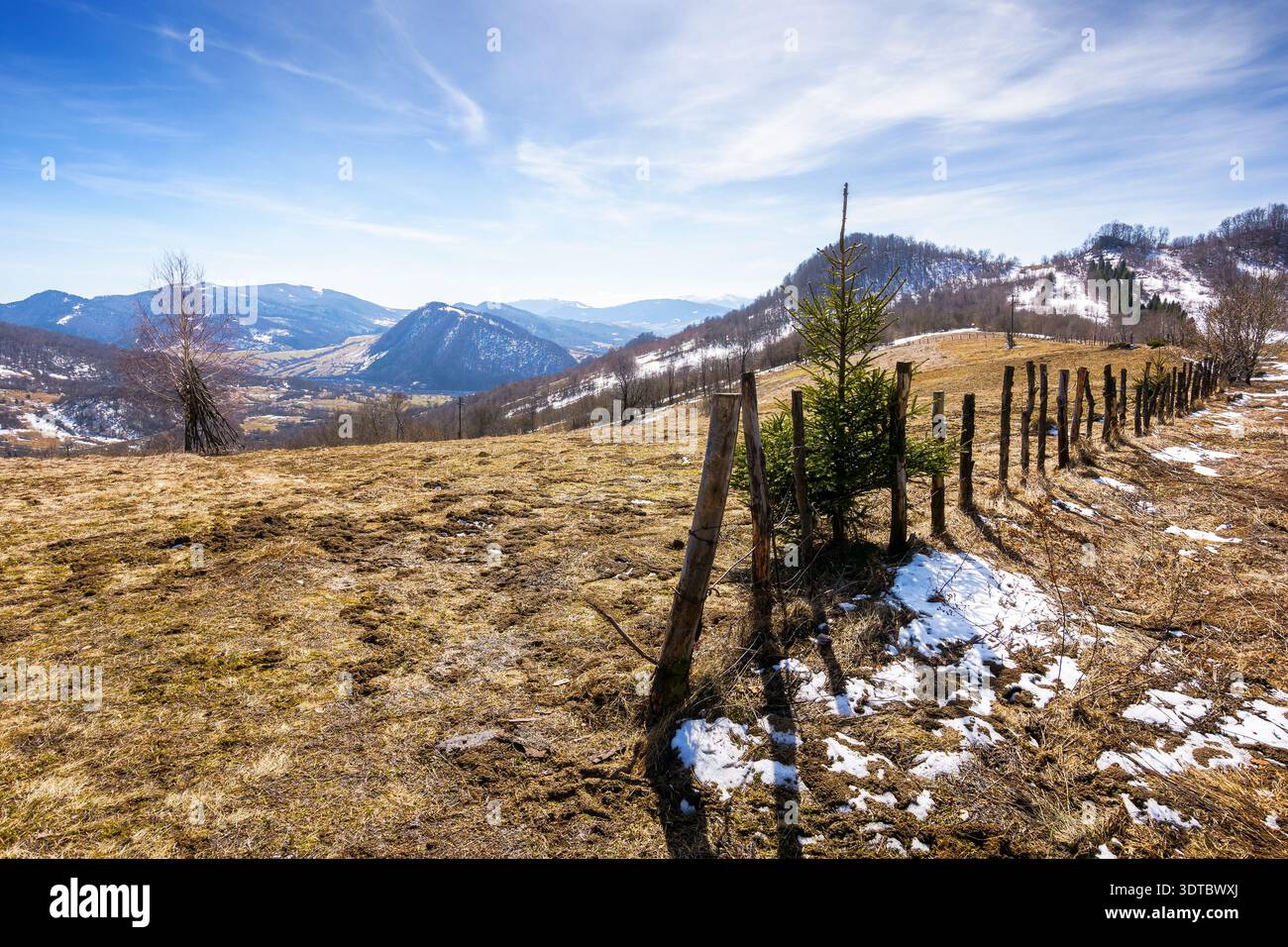 rural landscape of carpathian mountains in early spring under blue sky. snow covered hill with barbed wire fence on a sunny day. green environment sus Stock Photo