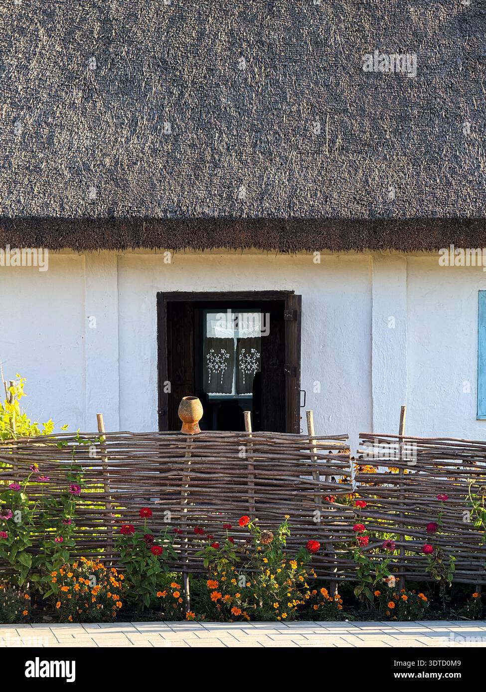 Traditional ukrainian house featuring thatched roof and wattle fence Stock Photo