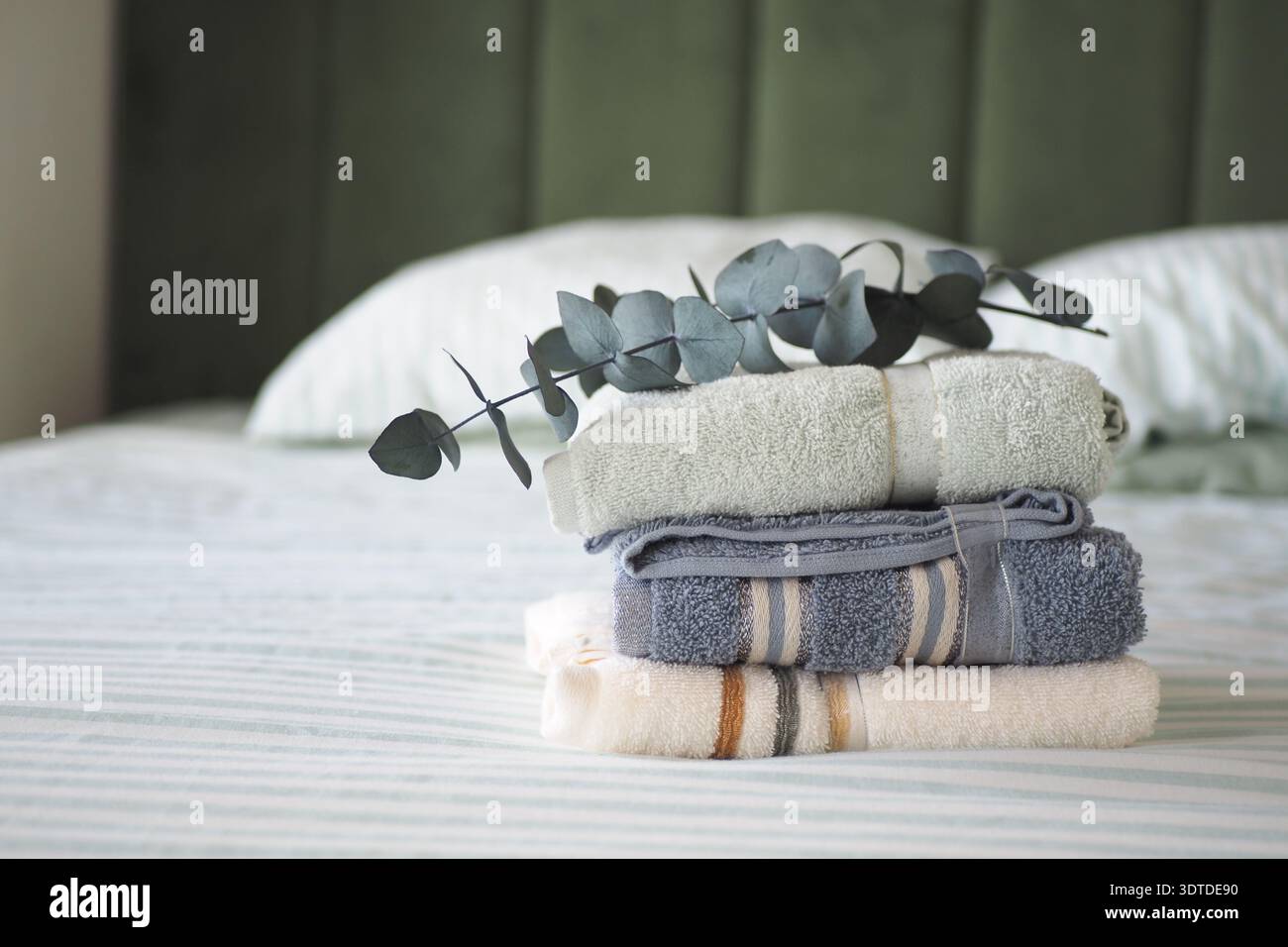 Freshly folded towels on a bed with green background Stock Photo