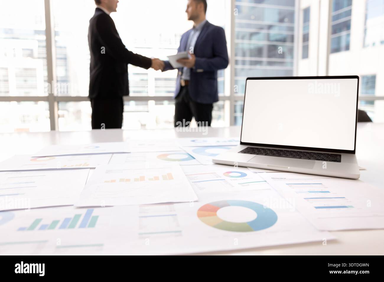 Laptop screen with white mockup, statistical data displaying in papers Stock Photo