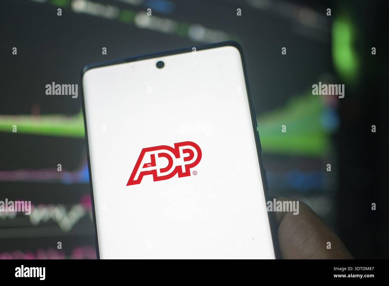 A hand holding a smartphone displaying the ADP logo in front of stock ...