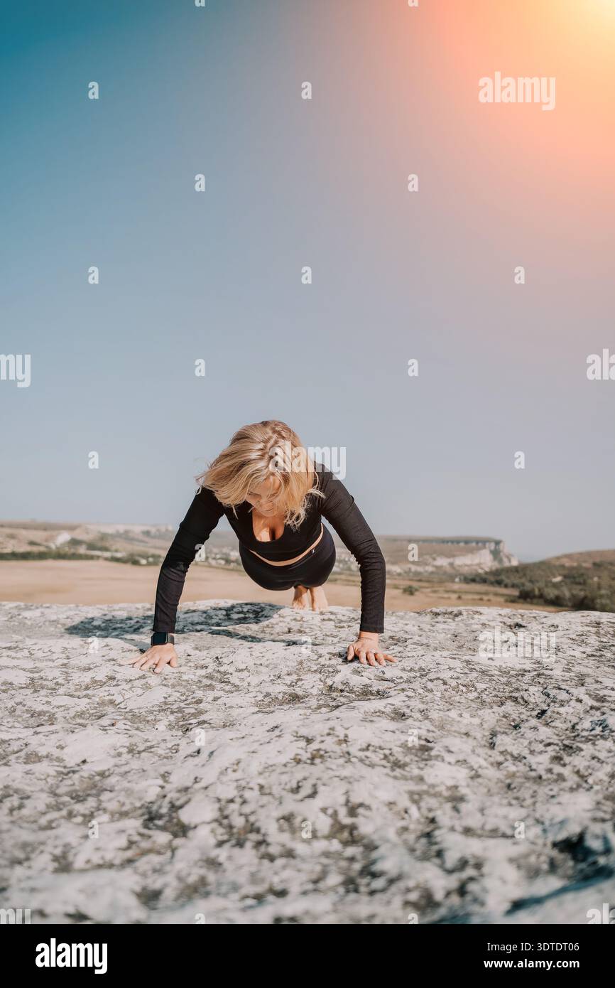 Woman Doing Push-Ups on a Rocky Cliff with a Blue Sky Stock Photo