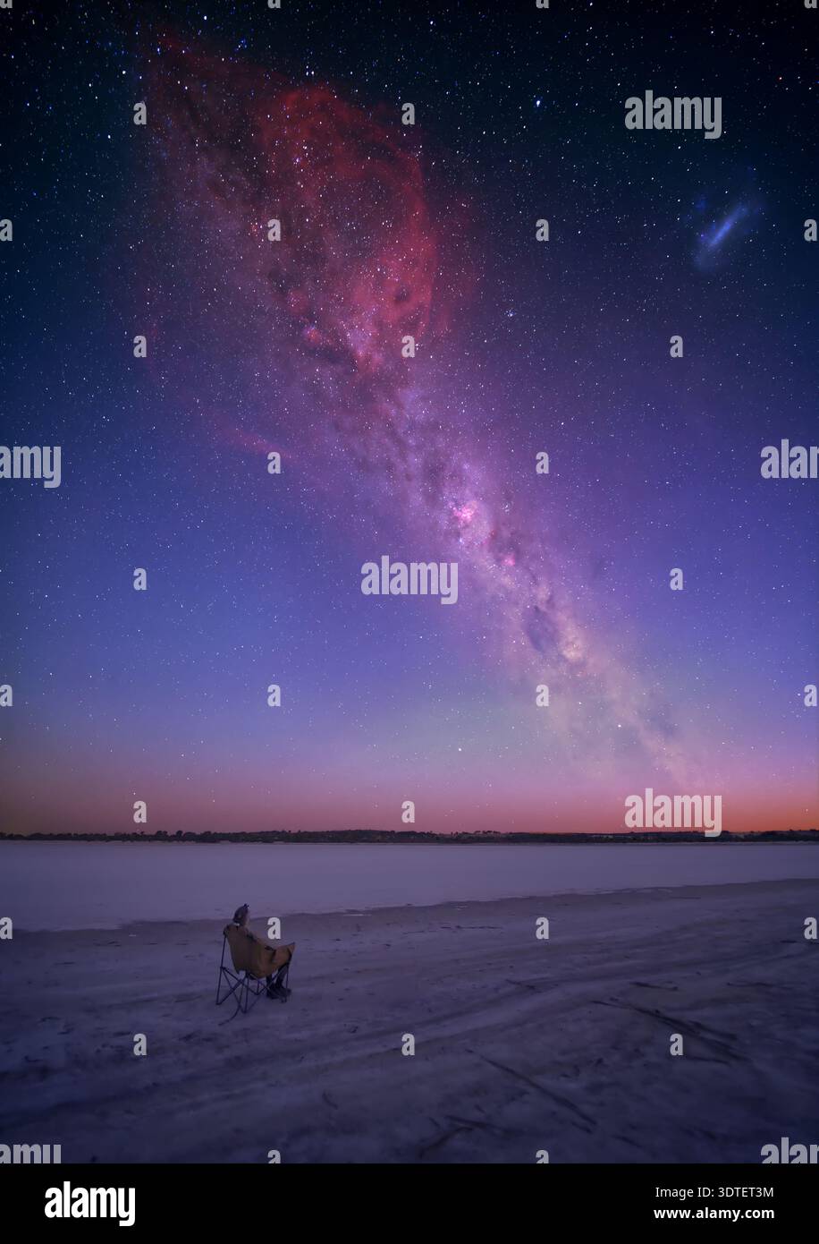 A person (the photographer) sits and watches the Milky Way rise above a dried out salt lake in the Wheatbelt of Western Australia. Stock Photo