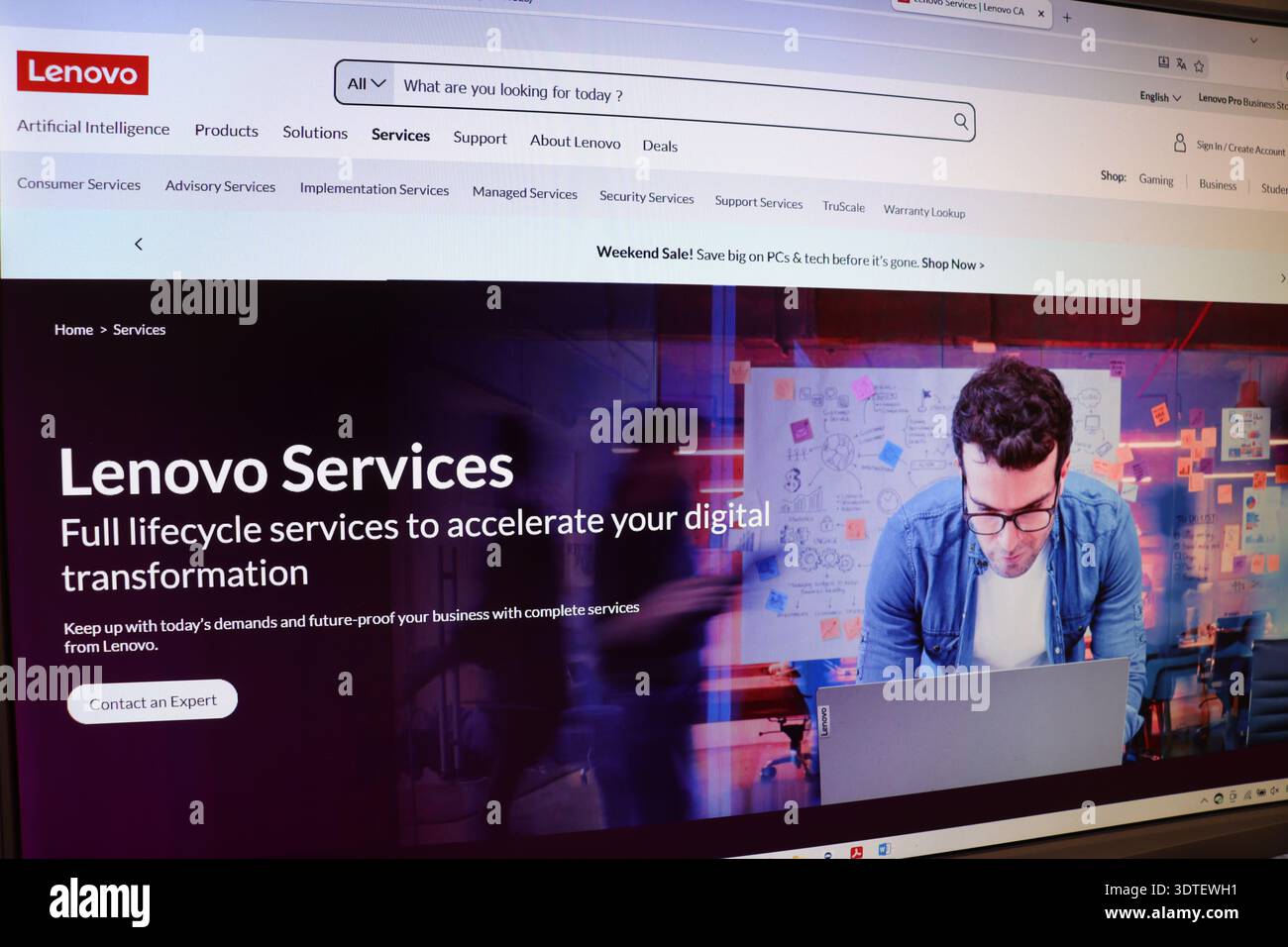 Computer screen displaying a website with a man working on a laptop, showing digital services and technology transformation solution. Stock Photo