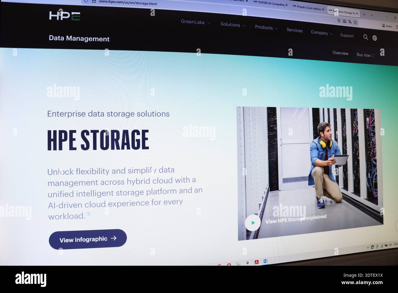 Computer screen displaying enterprise data storage solutions website with man in server room with tablet. Information technology concept. Stock Photo