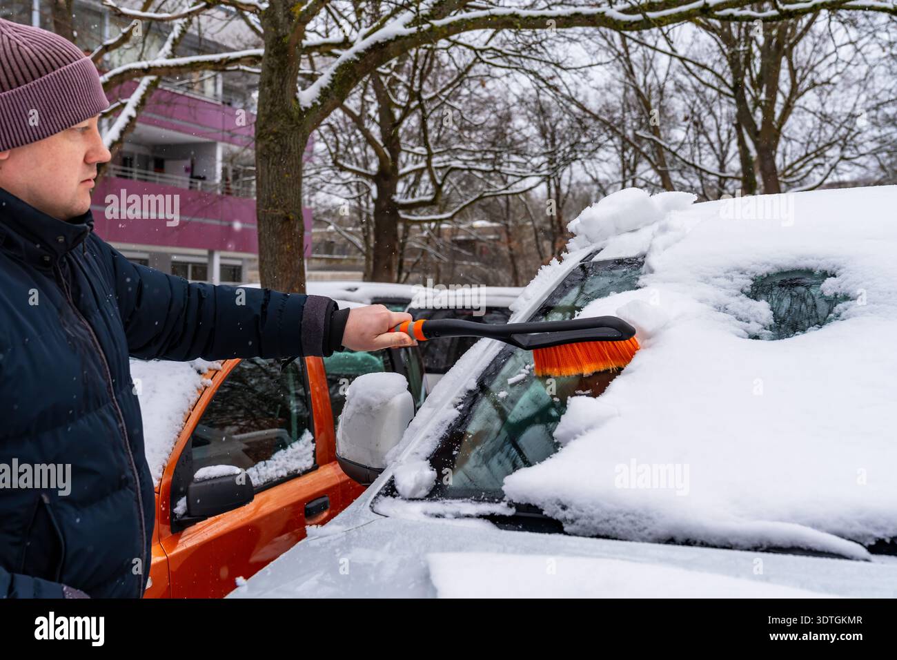 Routine of removing snow from vehicle during morning. Individual systematically brushing snow from car before starting daily journey Stock Photo