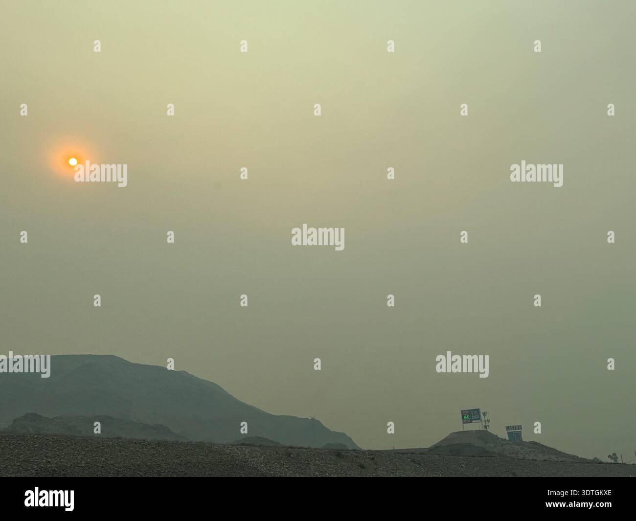 Hazy sun over desert highway with electricity transmission lines and mountains in the background in the American Southwest, Nevada, USA. - Smartphone Captured Stock Image