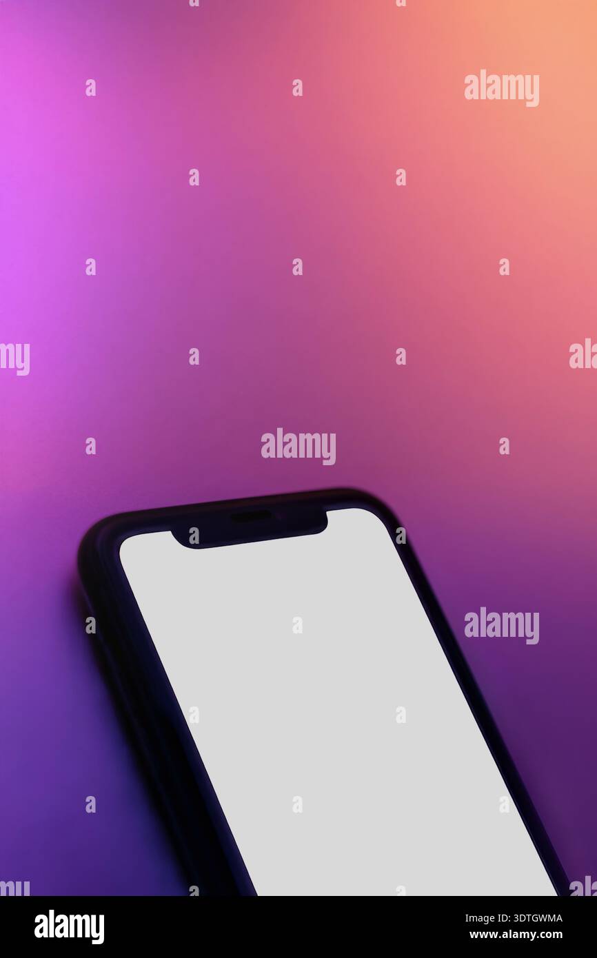 Close up of smartphone with white screen on pink purple neon surface. Copy space for app, product, or user interface presentation. Vertical banner of phone mock up with blank screen Stock Photo