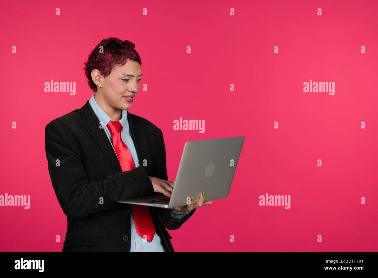 Young professional standing, typing on laptop, using technology Stock Photo
