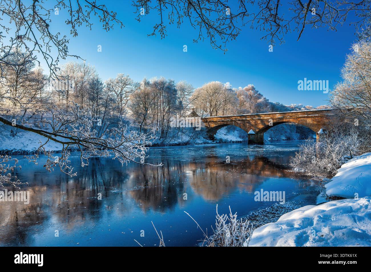 A view on a frozen winter morning with ice & snow looking over the River North Tyne & Bellingham Bridge in Northumberland Stock Photo