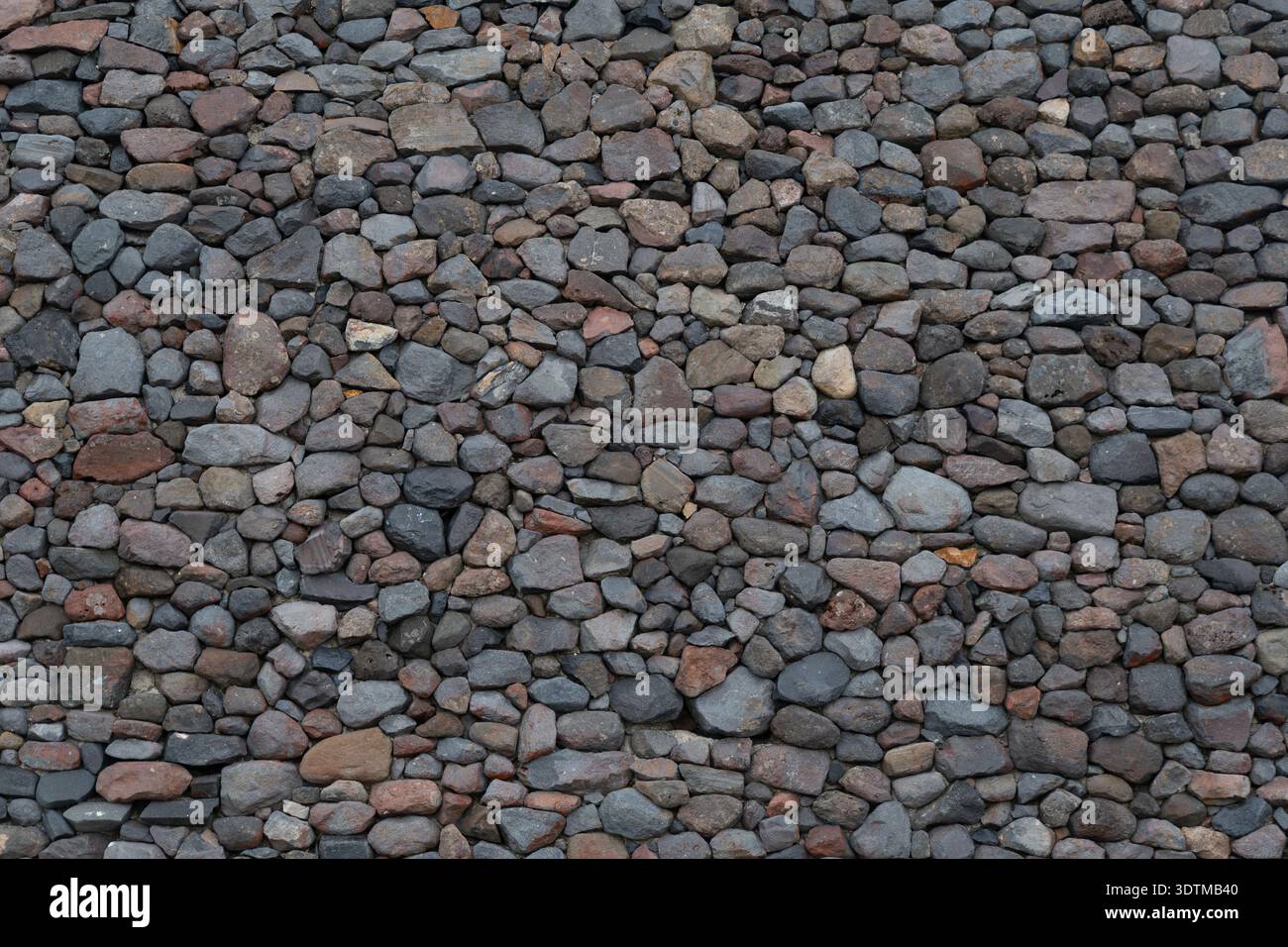 Rock wall made of small rocks on concerete background.  Background image, texture. Stock Photo