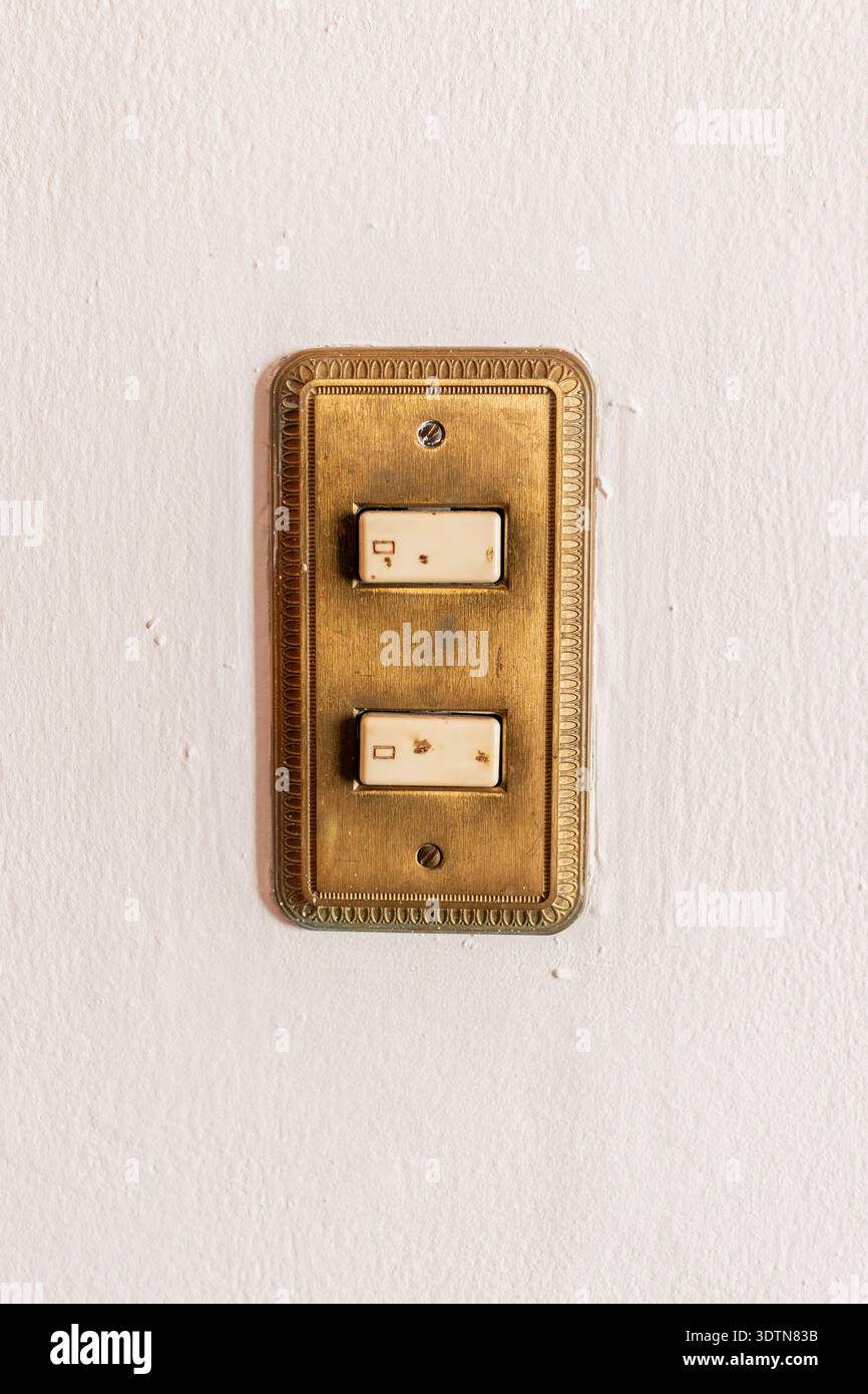 Vintage brass light switch on textured white wall Stock Photo