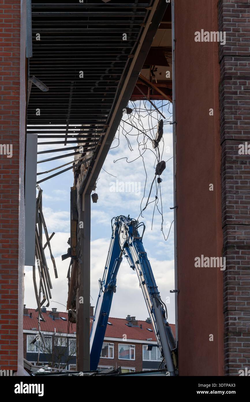 Window Frame Rabar large blue excavator arm is visible through a broken window frame, with ...