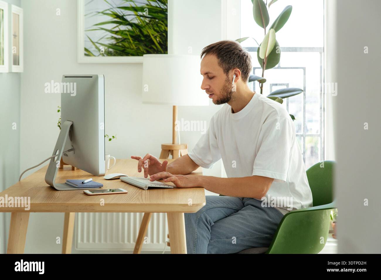 Man freelancer checking email in morning typing on wireless keyboard in home office busy with outsourcing or remote business occupation. Male freelance web developer work on computer programming app || Model released Stock Photo