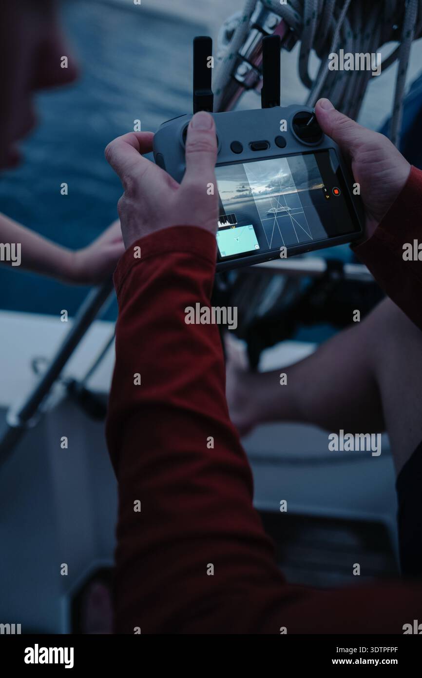 Man's hands holding drone controller on boat deck flying UAV whi Stock Photo