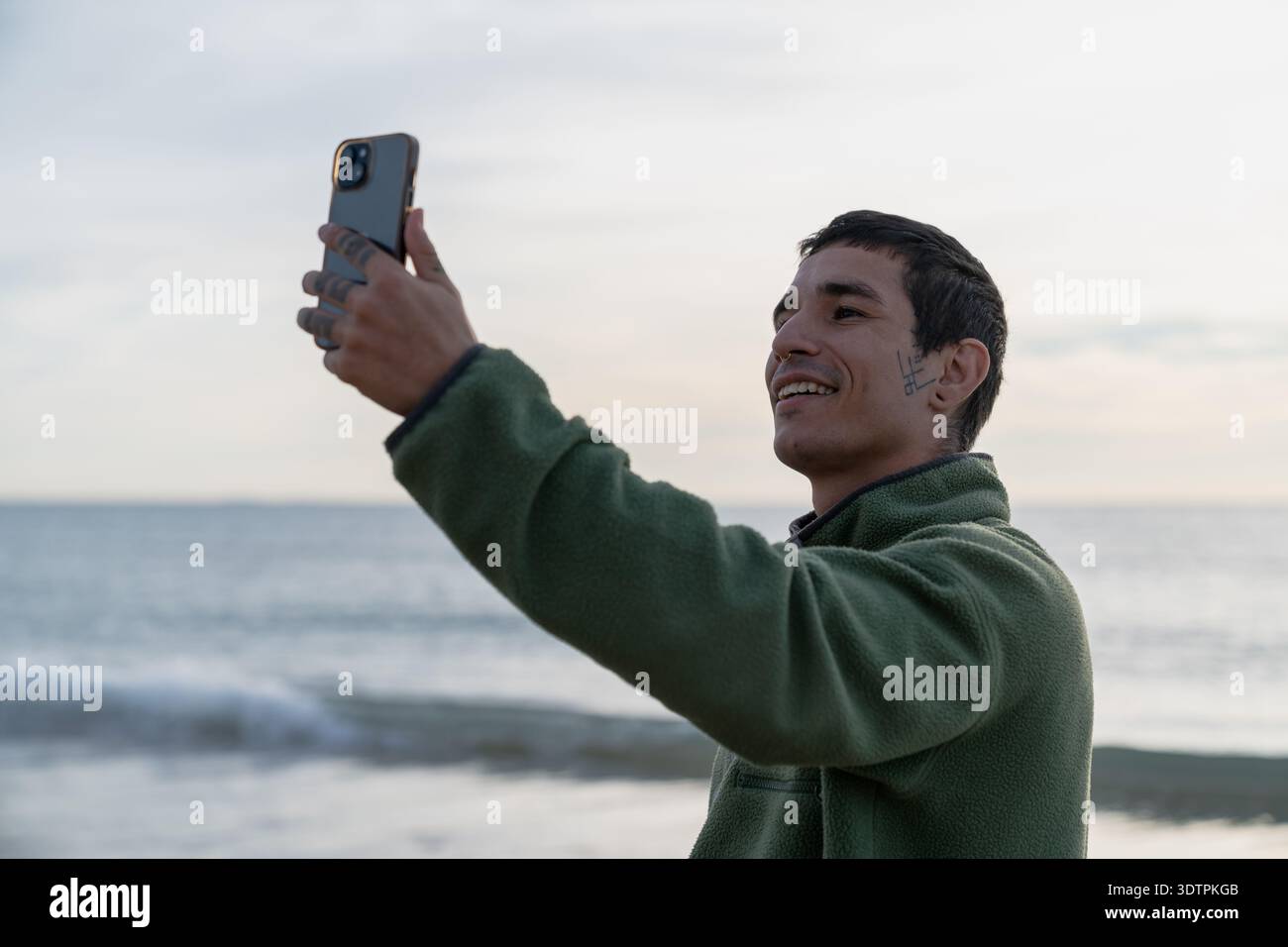 Young man taking selfie on beach using smartphone Stock Photo