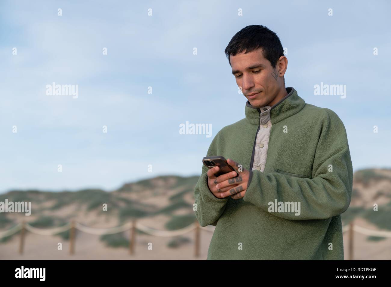 Young man using smartphone on sandy dunes Stock Photo