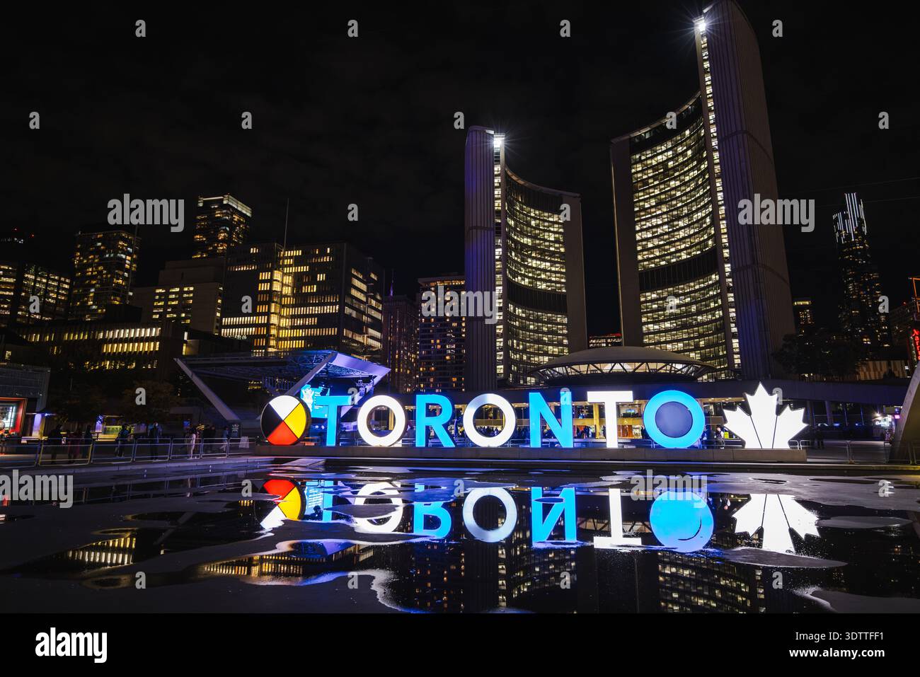 Night view of illuminated Toronto sign with city skyline and ...