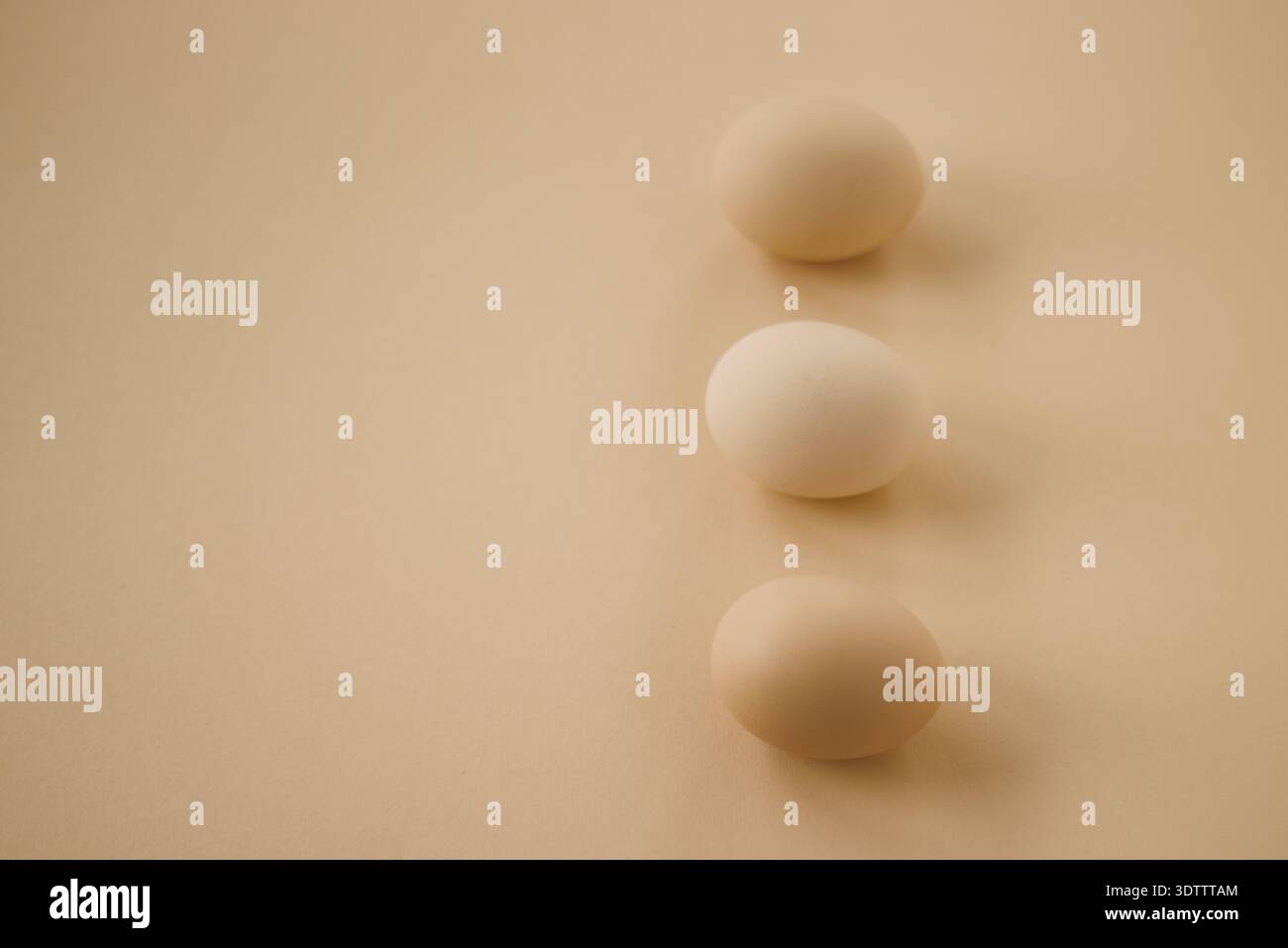 Three brown eggs on minimalist beige background Stock Photo