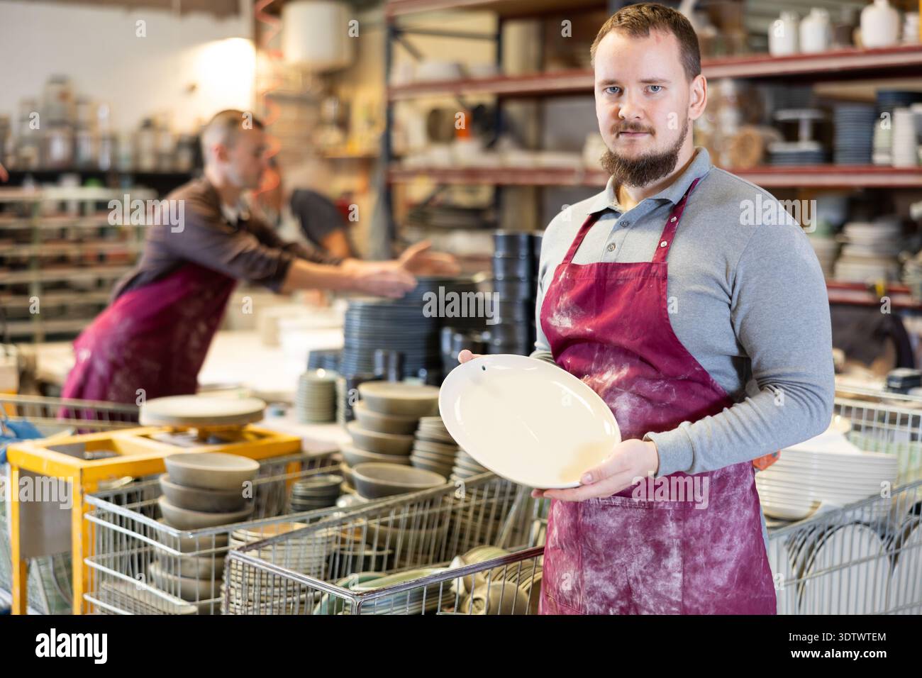 Enthusiastic ceramicist demonstrating handcrafted plates in ceramic studio Stock Photo