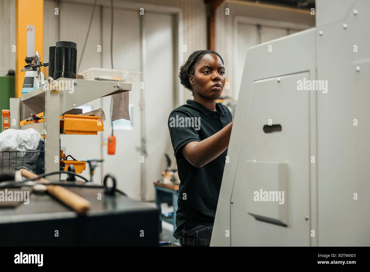 Young female worker operating machine in factory Stock Photo