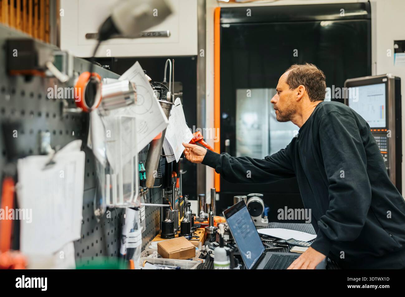 Manufacturing Factory Operative Mature male operative reading paper while working in manufacturing ...
