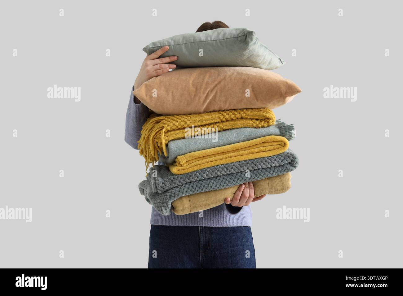 Woman with stack of plaids on light background Stock Photo