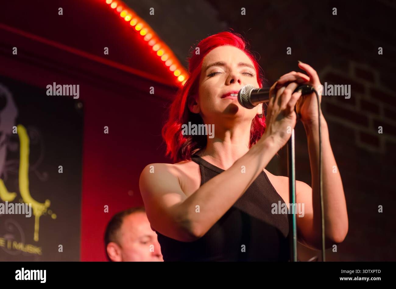 Female singer with red hair passionately singing into a microphone on ...