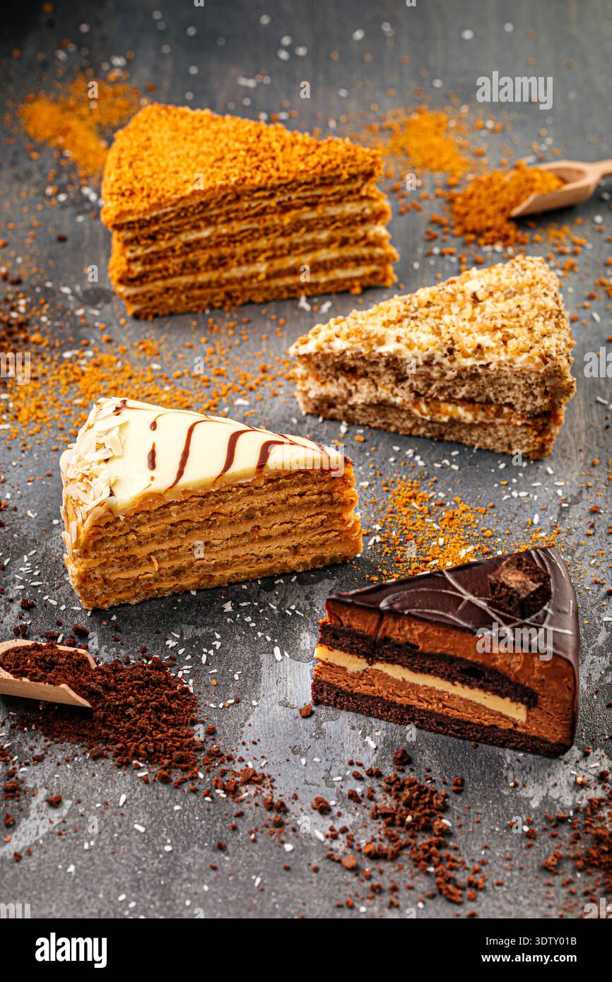 Assorted layered cake slices on dark table Stock Photo
