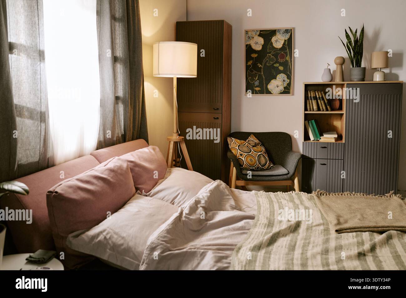 Cozy Modern Bedroom Interior Featuring Sunlight Streaming through Window Stock Photo