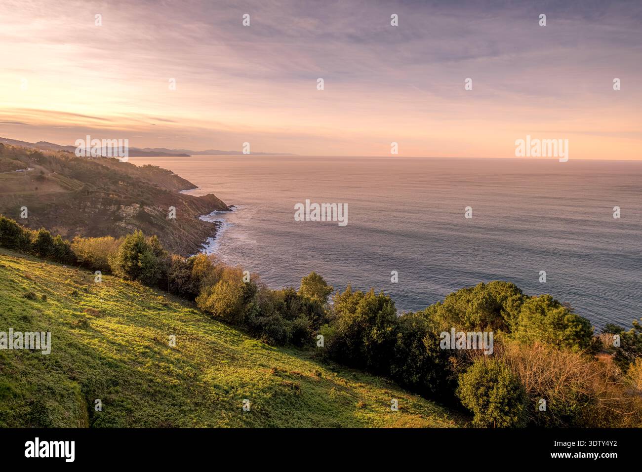 Sunset over the Cantabrian Sea Coast, Lush Green Hills at Golden Hour, Atlantic Ocean View Stock Photo