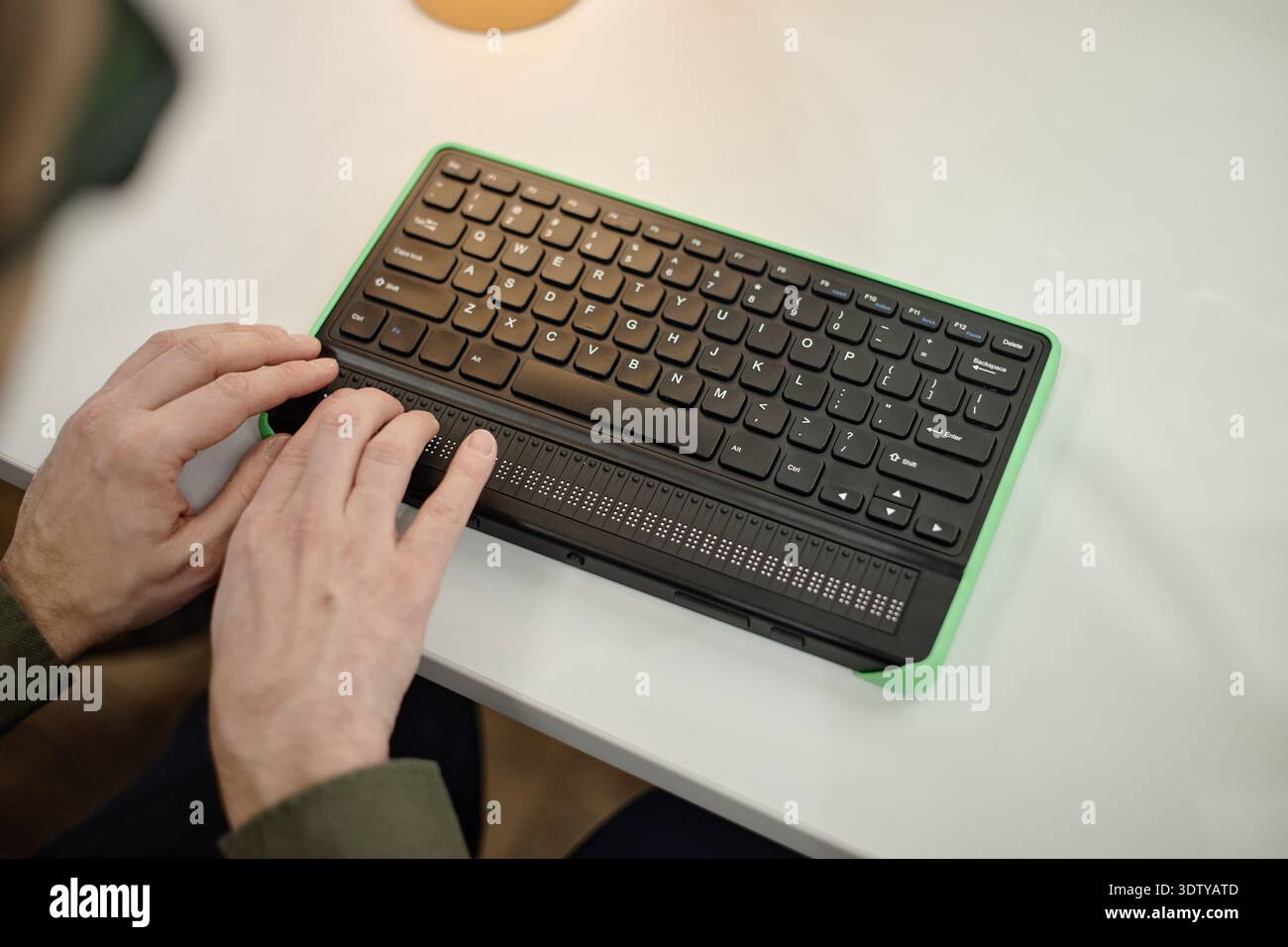 Young Adult Man Using Braille Keyboard Device While Reading in Library Stock Photo