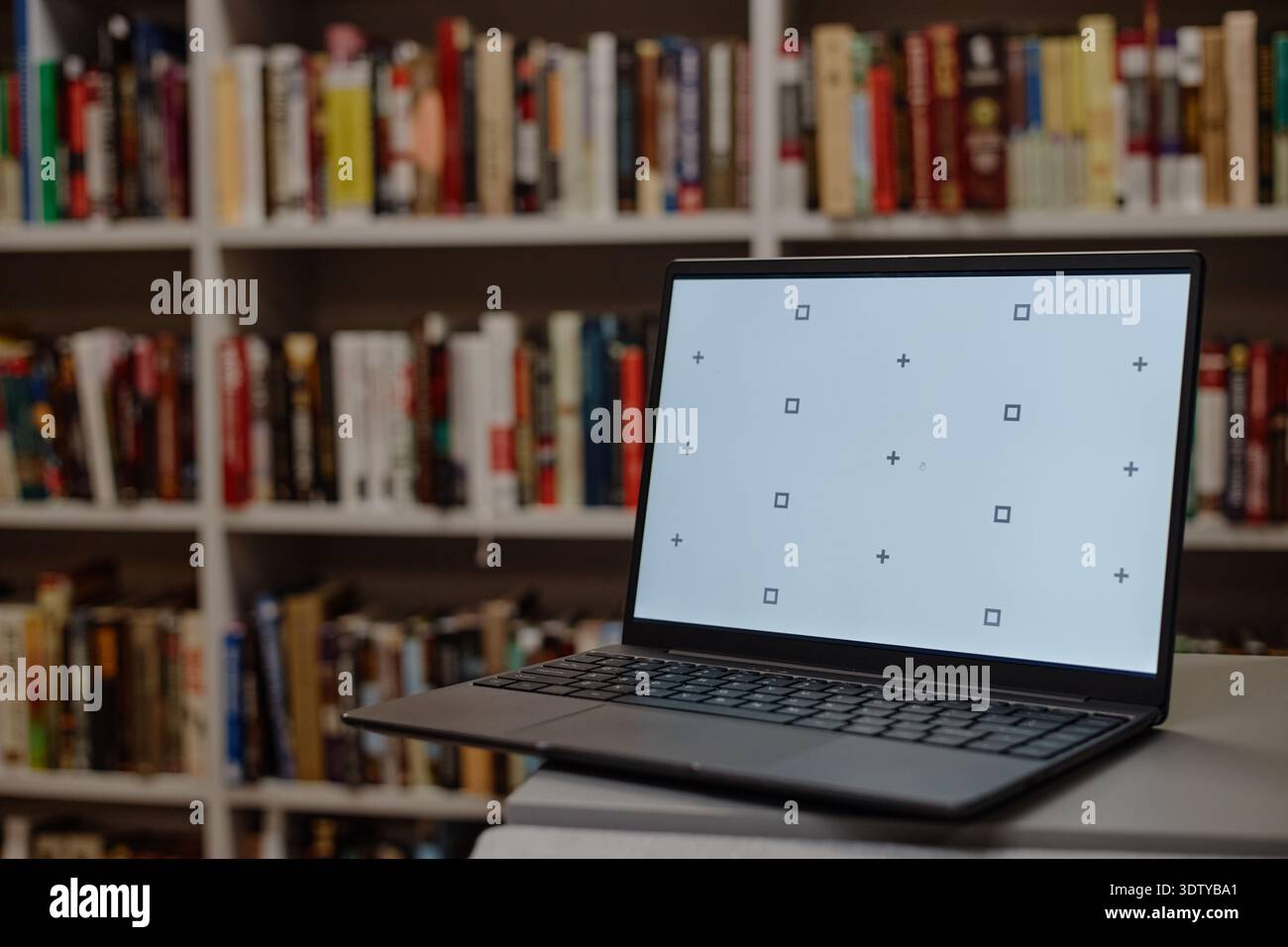 Laptop Displaying Blank Screen in Library Environment Stock Photo