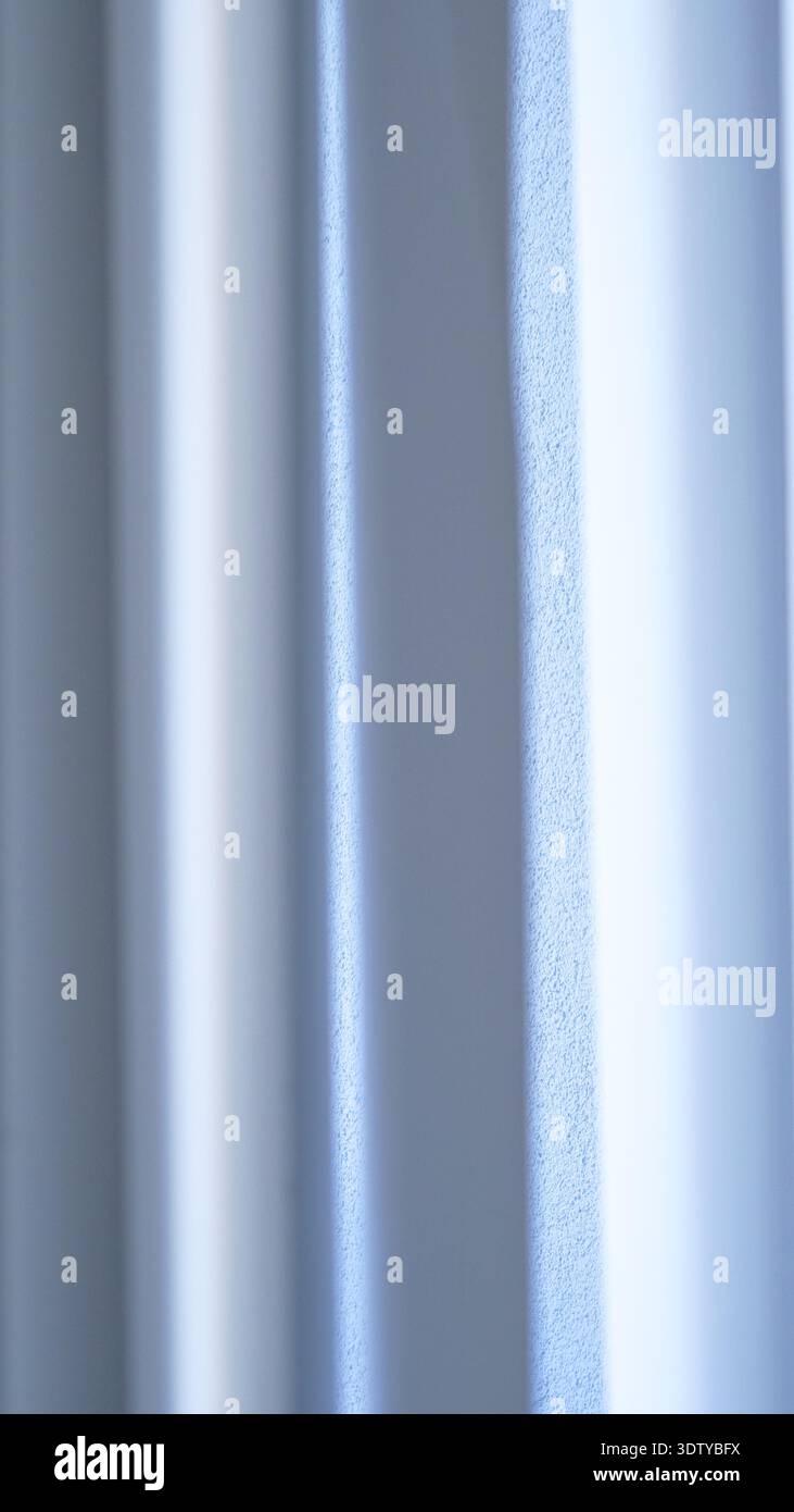 Textured white wall with vertical lines and soft light reflections creating a subtle pattern Stock Photo