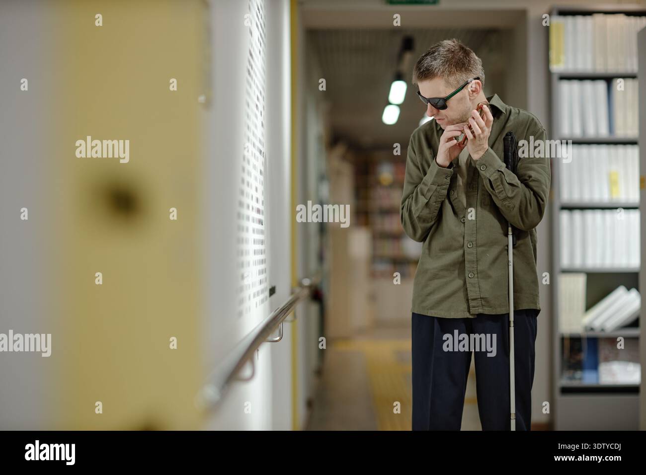 Young Man Using Cane Navigating Library as Blind Individual Stock Photo