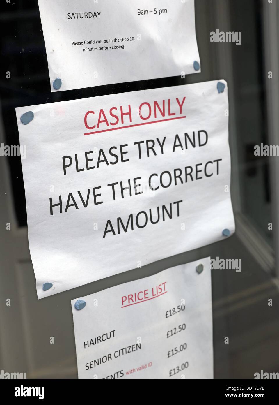 Cash-only notice and price list in the window of a barber shop in Beverley, East Riding of Yorkshire, England. Stock Photo