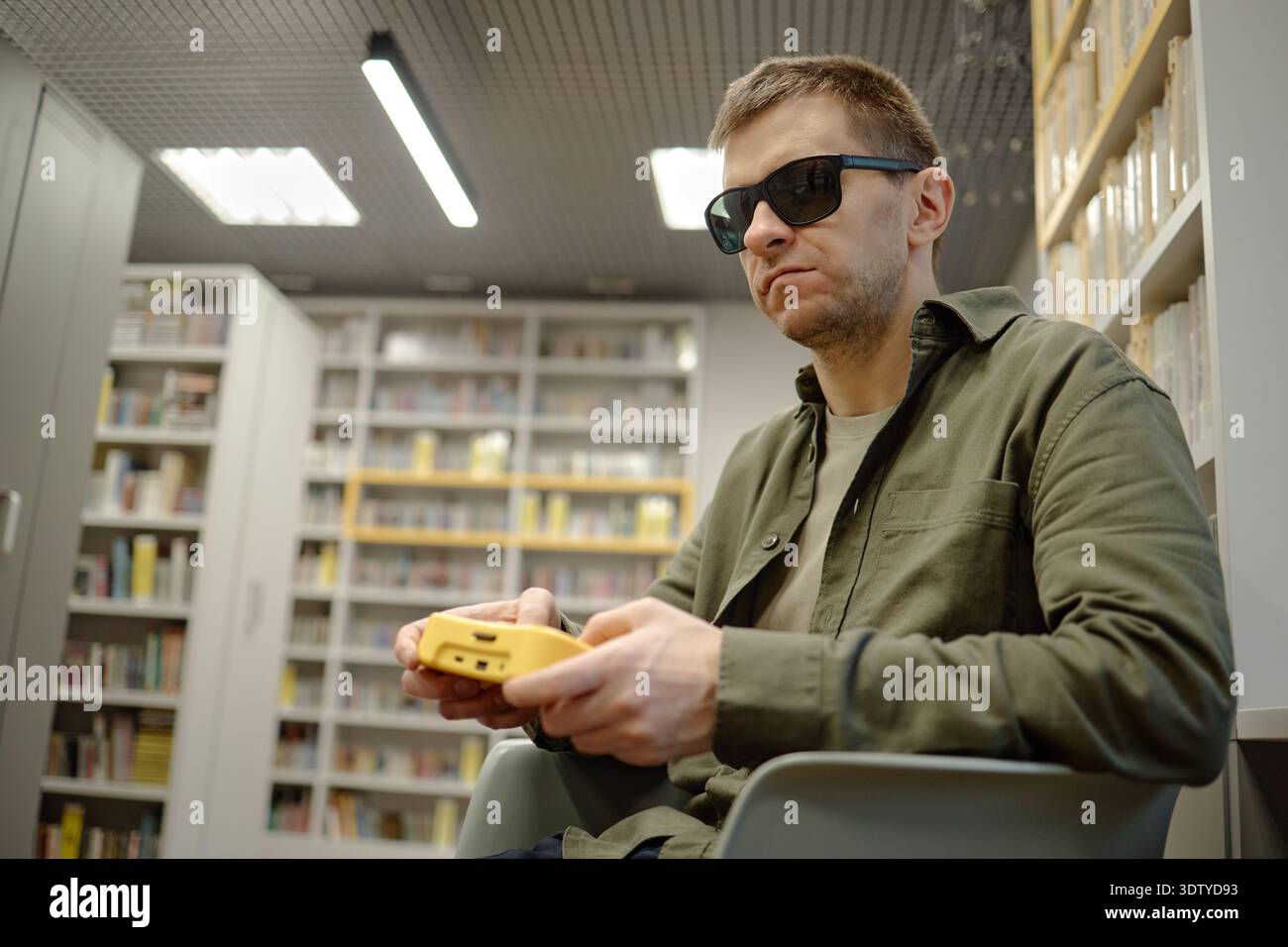 Middle Aged Man Wearing Sunglasses Using Braille Device in Library Stock Photo