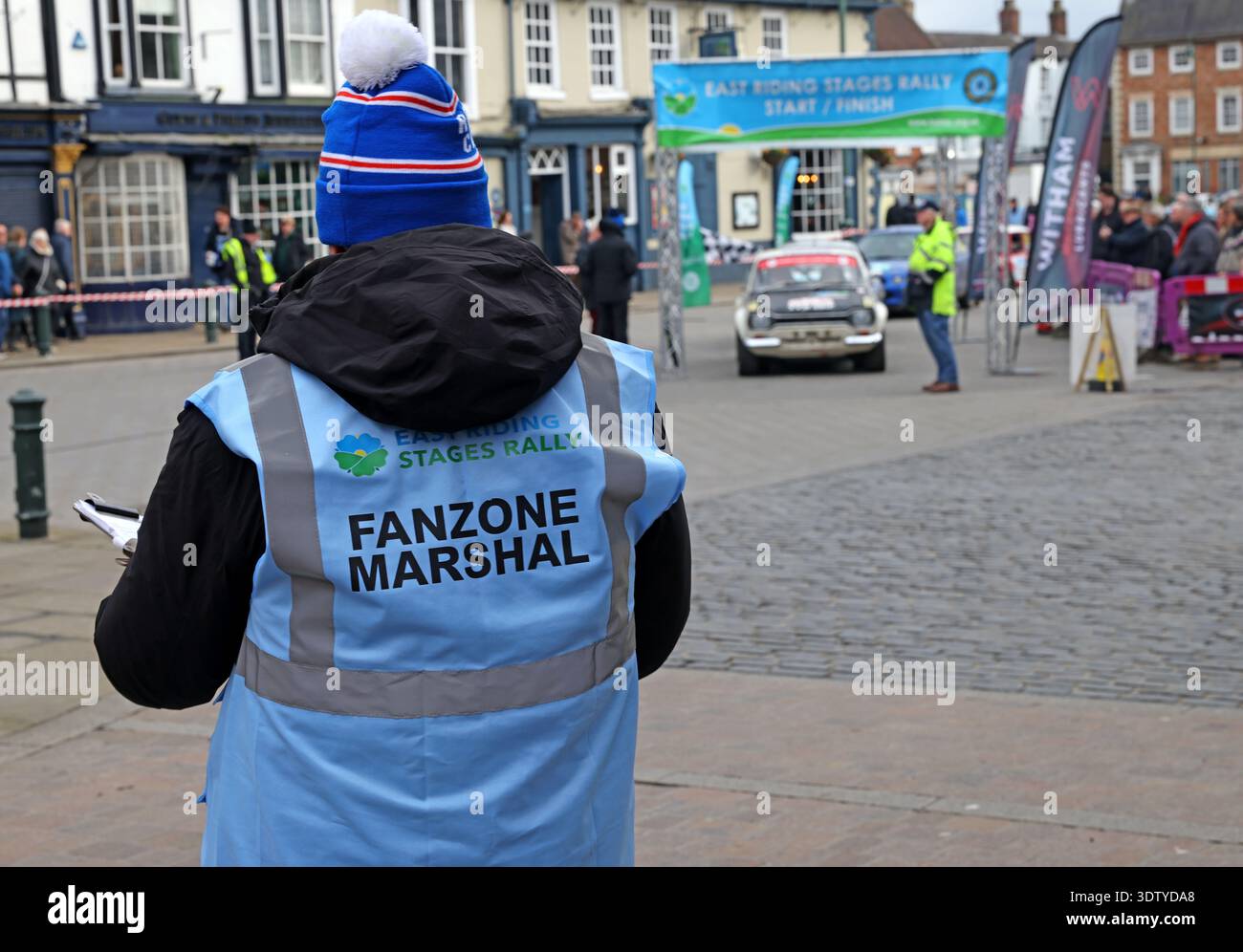 Fanzone marshal at the East Riding Stages Rally in Beverley, East Riding of Yorkshire, with rally car and start or finish area in the background. Stock Photo
