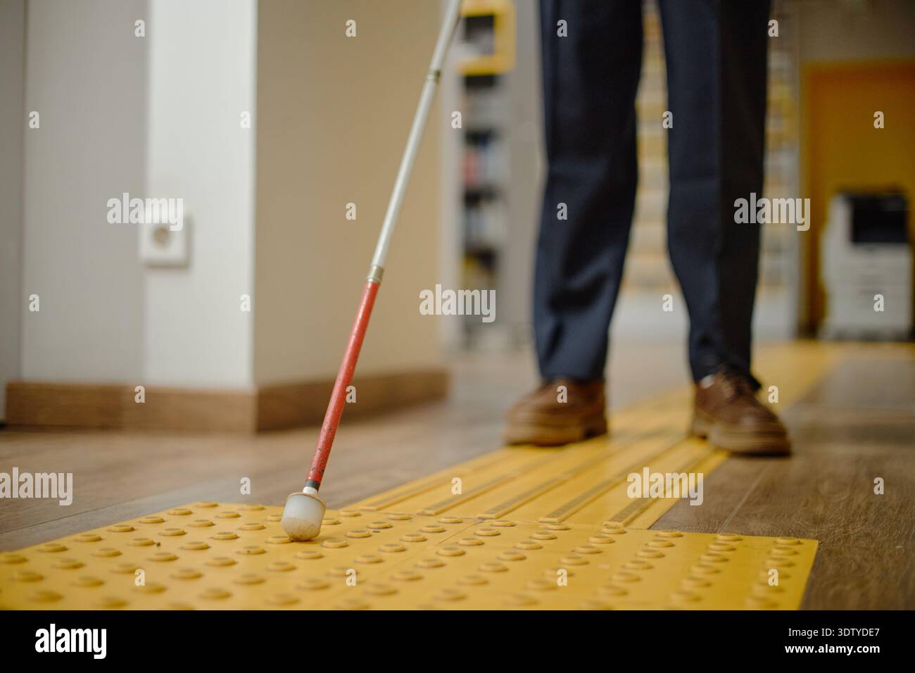 Man Navigating Library with Cane Using Tactile Path Stock Photo
