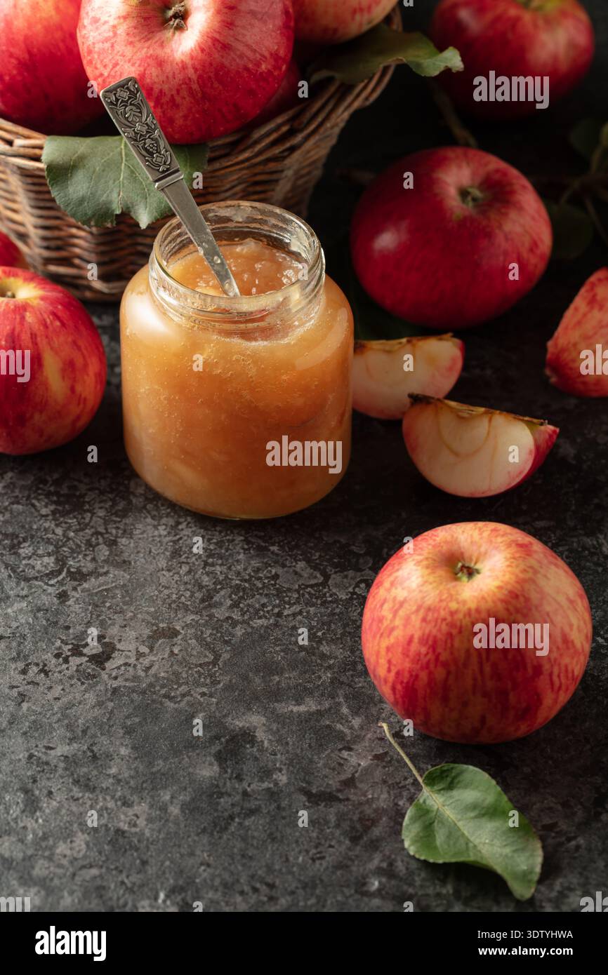 Apple jam and red fresh apples on a black stone table. Stock Photo