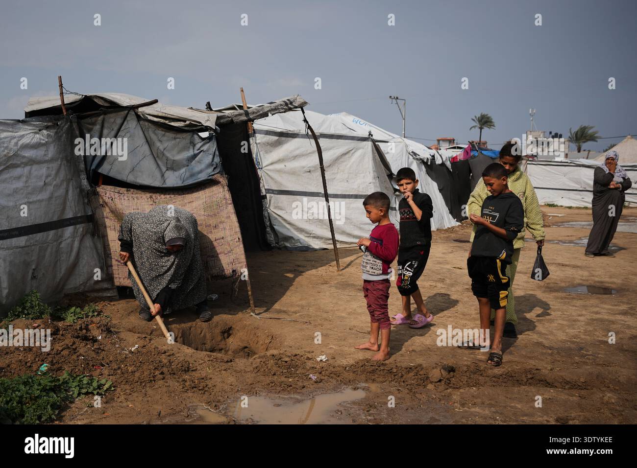 Displaced Palestinian Lubna Abu Sirya, digs a small channel to drain ...
