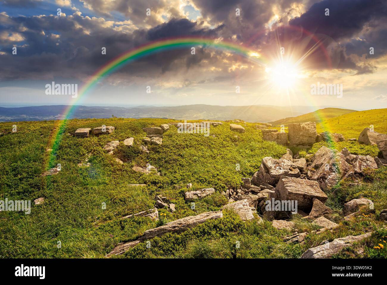 grassy alpine meadow in carpathian mountain landscape at sunset. sharp rocks and huge boulders among green grass on rolling hills in evening light. op Stock Photo