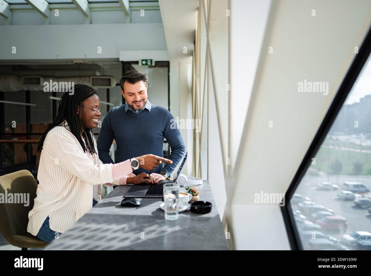 Diverse business professionals collaborating on laptop in modern office Stock Photo