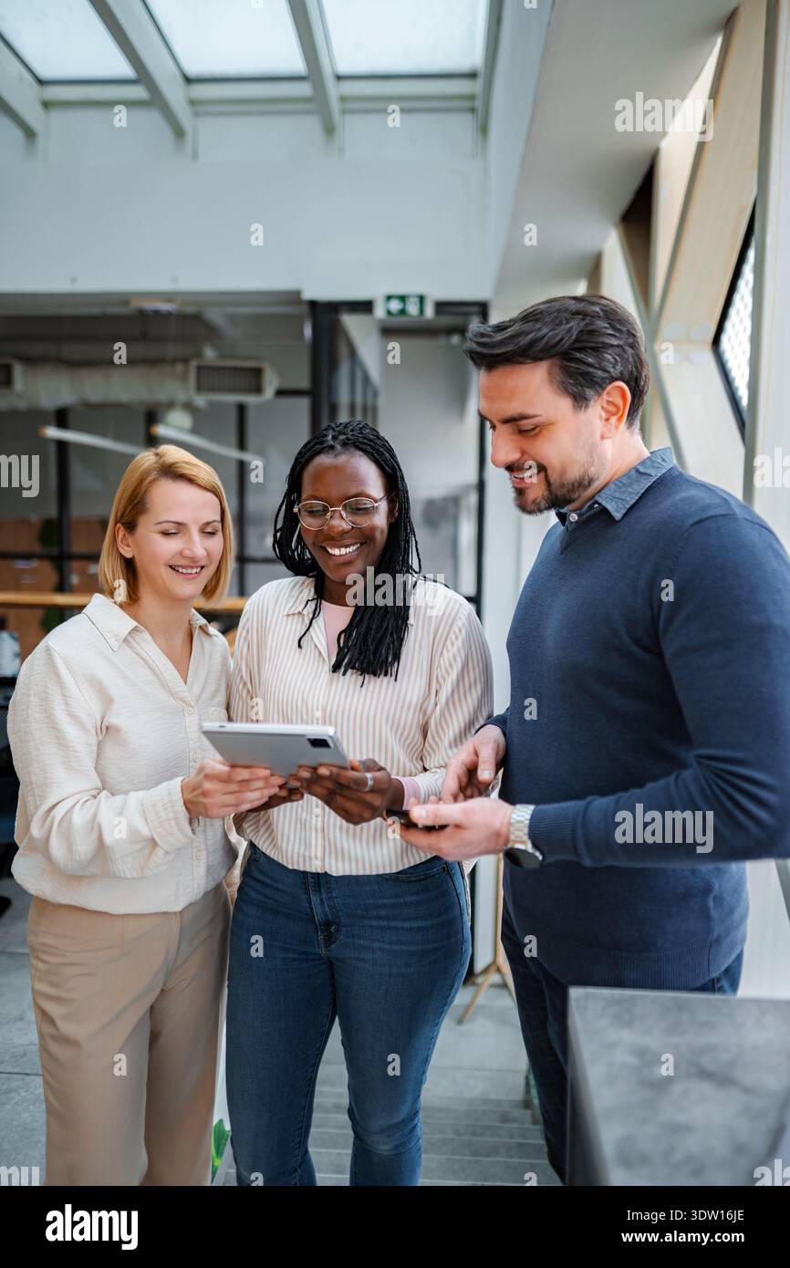 Diverse business professionals collaborating smiling using digital tablet Stock Photo