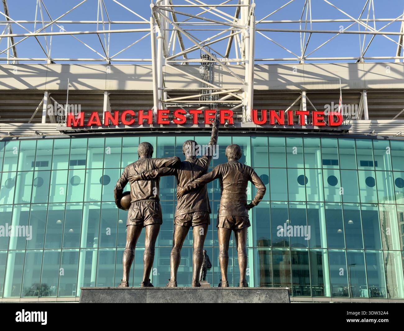 MANCHESTER, ENGLAND: FEBRUARY 17, 2026: Three memorial statues with Manchester United red lettering signage at Old Trafford stadium - Smartphone Captured Stock Image